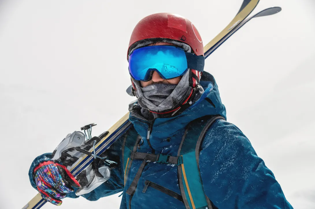 Man holding his skis and wearing goggles