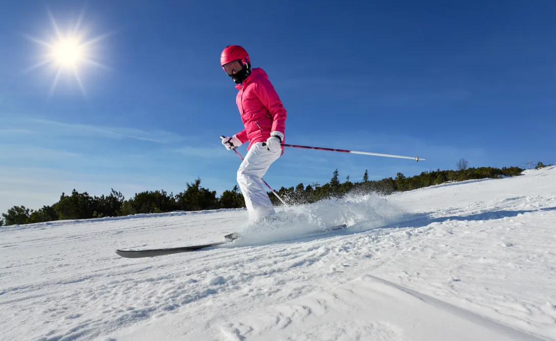 woman in pink winter jacket and helmet skiing 